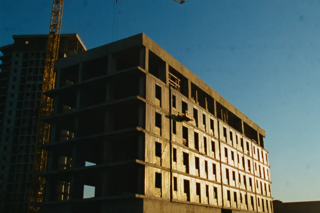 Edifício residencial em obra, com estrutura de concreto aparente e andaimes